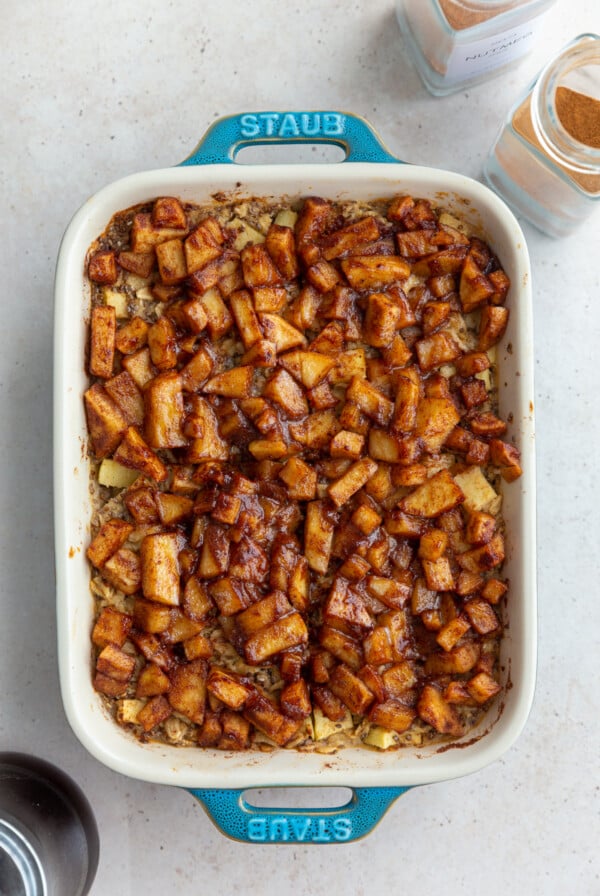 baked oatmeal topped with cinnamon apple chunks in a small teal baking dish