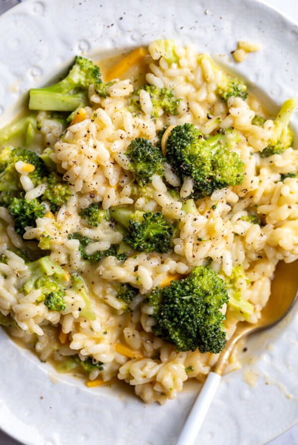 Broccoli Cheese Risotto served in a white bowl with a spoon.