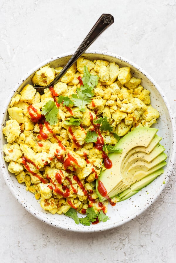 Tofu scramble topped with ketchup and served with avocado.
