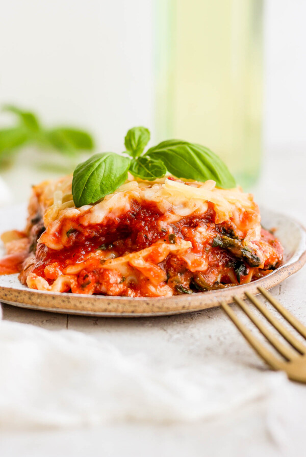 Vegan lasagna on a plate garnished with basil.