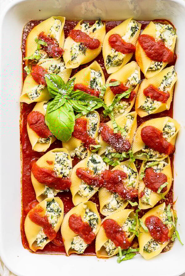 Vegan stuffed shells covered in sauce and garnished with basil.